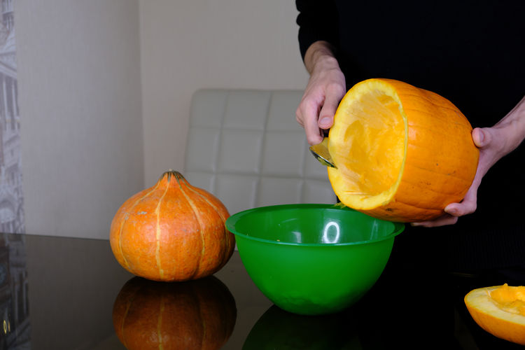 Midsection of man holding orange slices in bowl on table