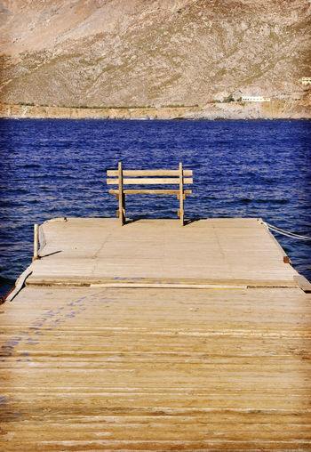 Wooden pier over sea against blue sky