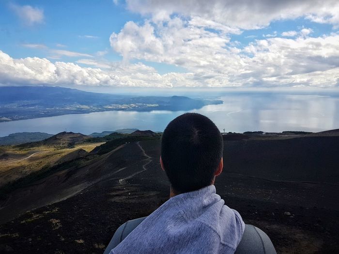 Rear view of man looking at sea against sky