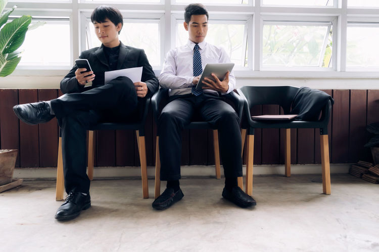 Businessmen using technologies while sitting in office