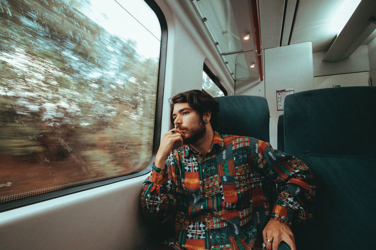 Young man looking through train window
