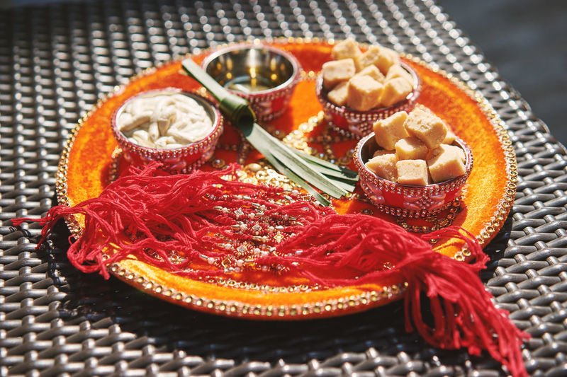 High angle view of rakhis with sweet food in plate during raksha bandhan on table