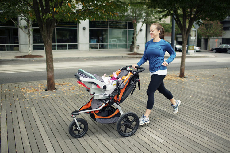 Cheerful woman looking at baby in while running on floorboard