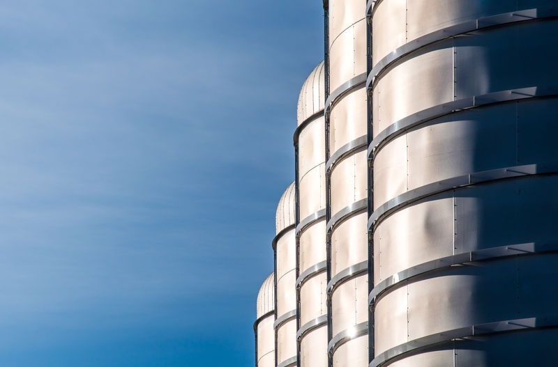 Low angle view of storage tanks against blue sky