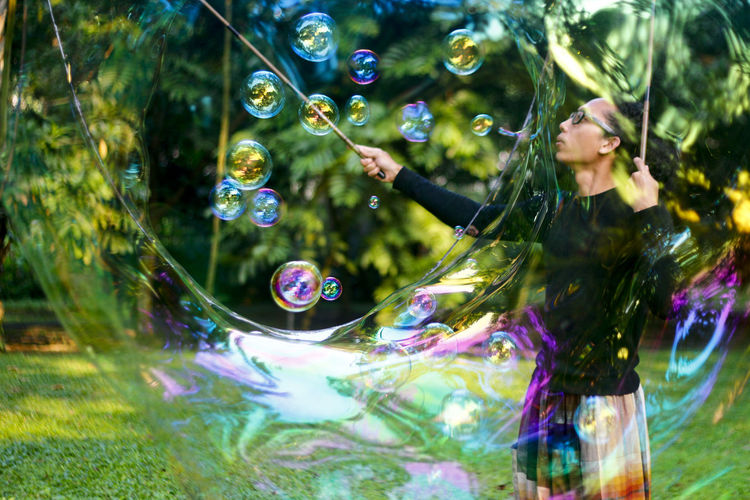 Street artist making rainbow bubbles at park 