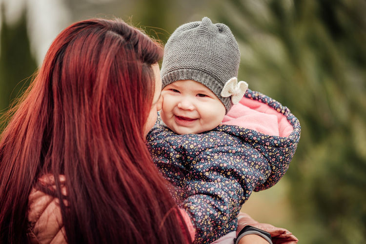 Smiling mother with daughter outdoors during winter