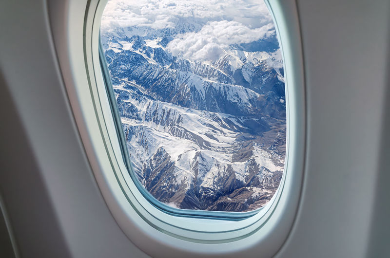 Airplane window view at snowy mountains
