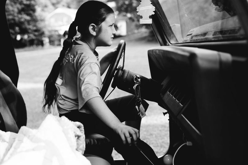 Side view of girl sitting in jeep