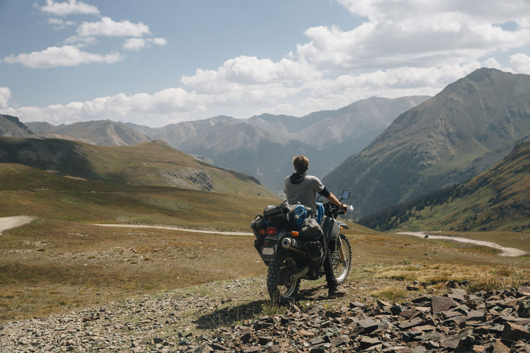 Rear view of men riding motorcycle against mountain range