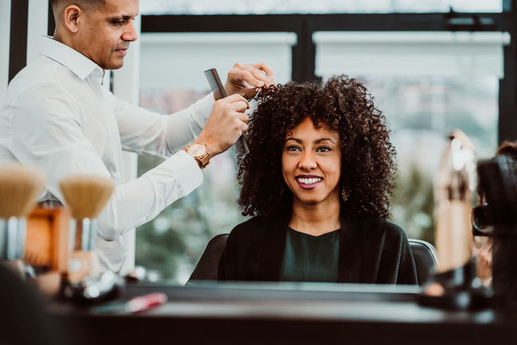 Barber cutting woman hair in salon