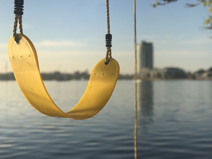 Close-up of yellow swing against river 