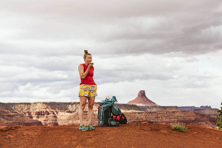 Tired female hiker eats apple during a long day backpacking in desert