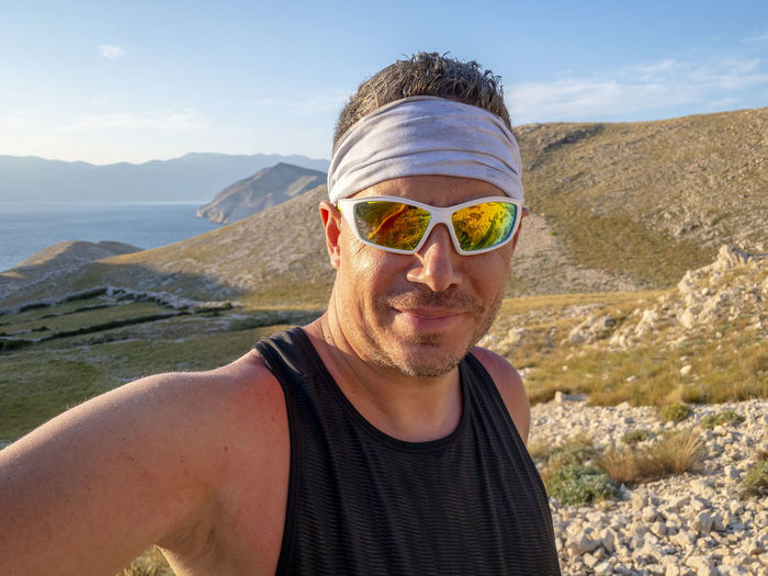 Portrait of man wearing sunglasses against mountain and sky