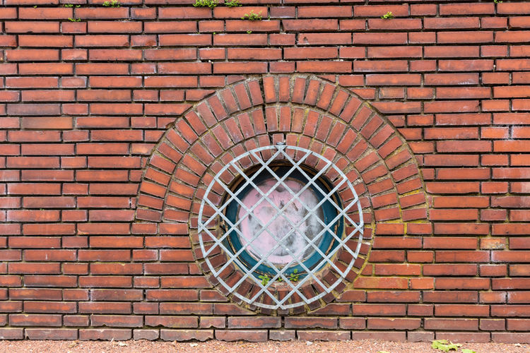 Metal grate on red brick wall