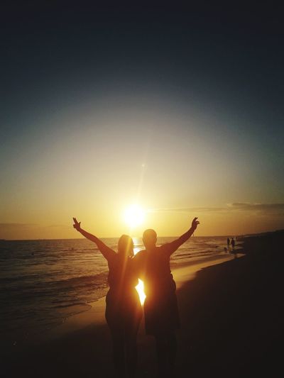Silhouette people at beach during sunset
