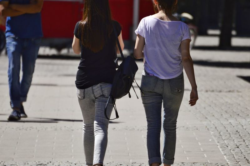 Rear view of women walking on sidewalk