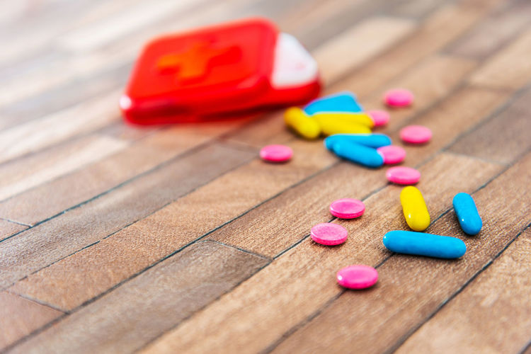 Close-up of multi colored pills with container on table