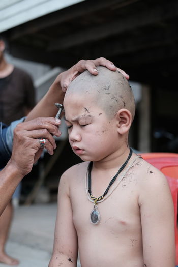 Close-up of barber shaving head of boy