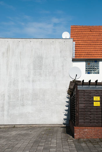 White wall by building against sky