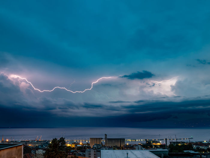 Lightning over illuminated buildings in city at night