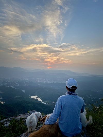 Rear view of man with dog against sky