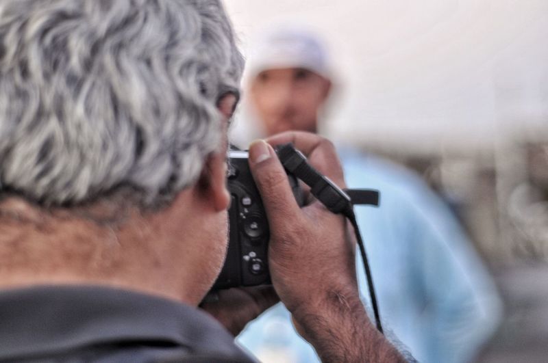 Rear view of photographer using dslr camera to photograph a man in traditional arab clothing