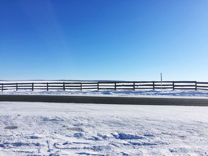 Frozen bridge against clear blue sky during winter