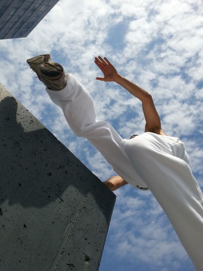 Man leaping between concrete plinth as viewed from underneath