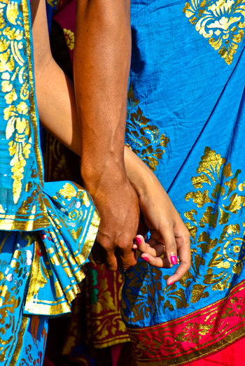 Two hands holding hands using traditional balinese cloth, indonesia.
