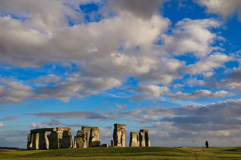 Scenic view of stonehenge in field against cloudy sky