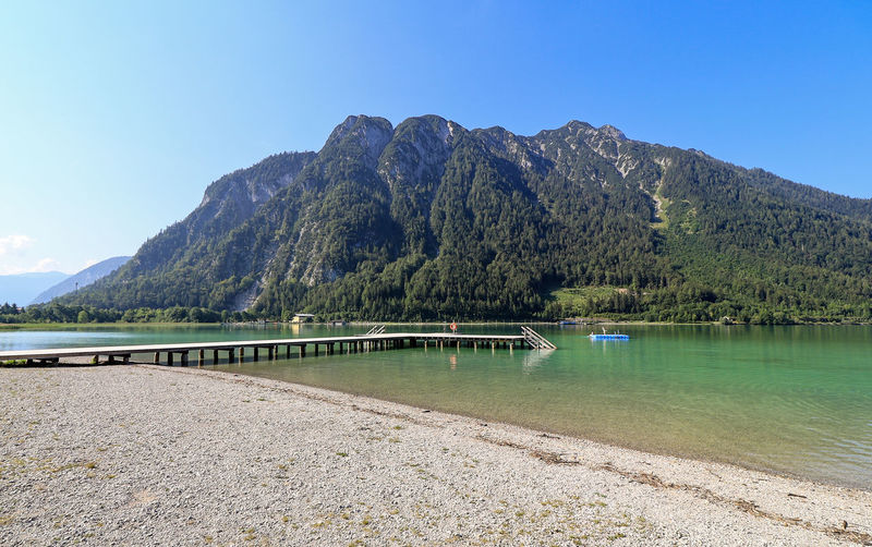 Scenic view of lake and mountains against clear blue sky