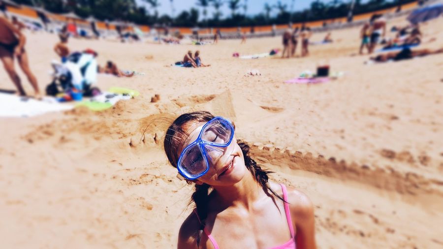 Girl wearing swimming goggles while standing on shore at beach