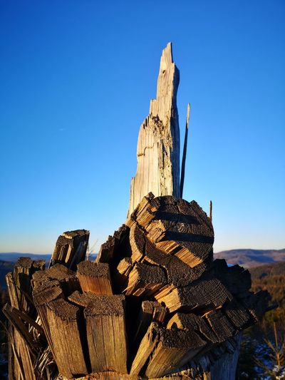 Low angle view of logs against clear blue sky