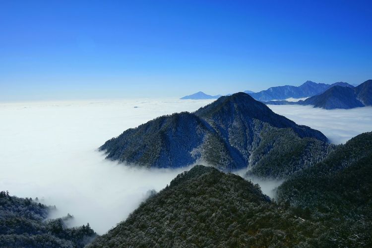 Scenic view of mountain against clear blue sky and clouds