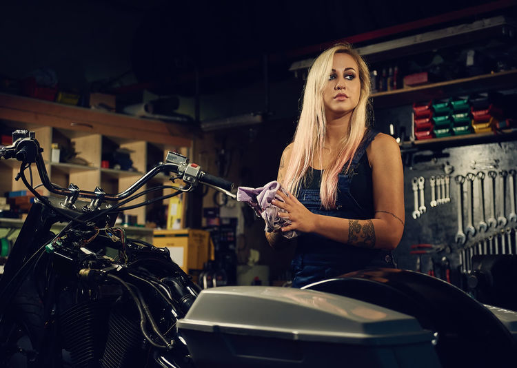 Young woman looking away while standing by motorcycle in garage