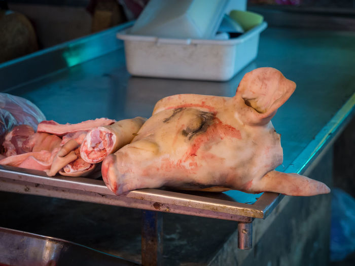 Close-up of pig head and other body parts for sale at butchery on market, chiang mai, thailand