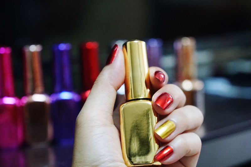 Cropped hand of woman holding nail polish bottle
