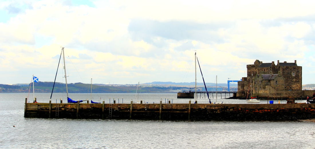 Sailboats moored in sea against buildings