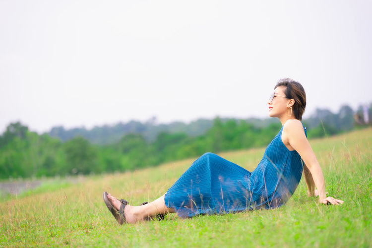 Side view of young woman lying on field
