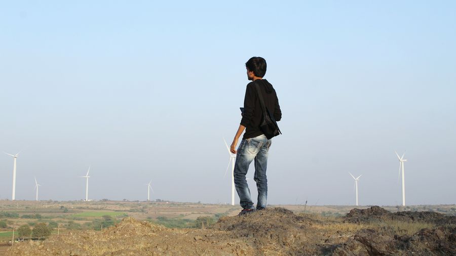 Man standing on field against windmills