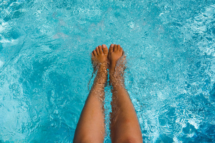 Low section of woman relaxing in swimming pool