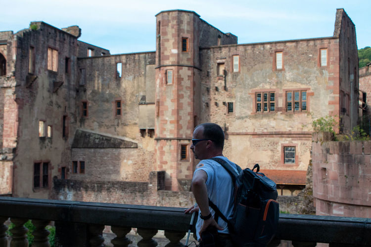 Rear view of man standing by building against sky
