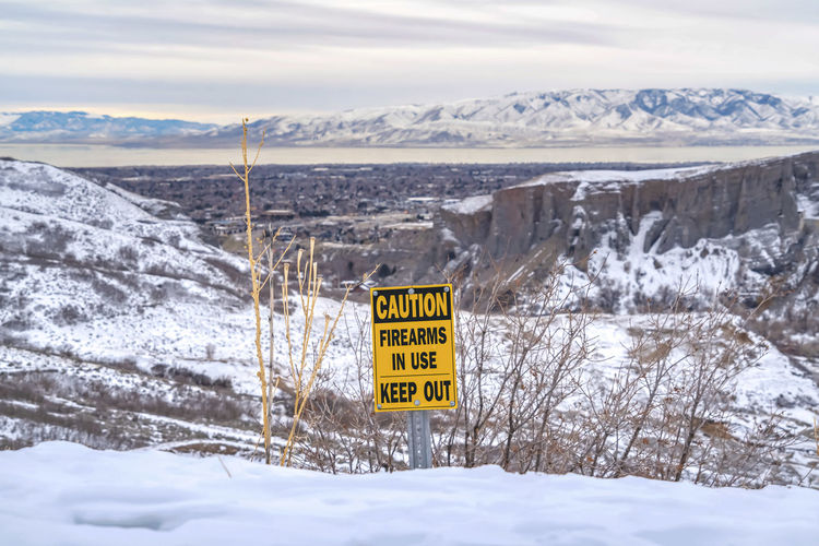 Information sign on snow covered landscape against sky