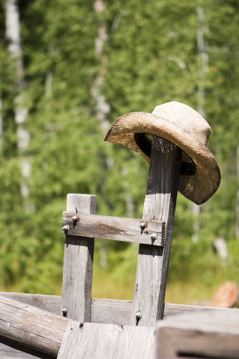 A straw cowboy hat resting on an old wooden post on an old kitchen wagon.