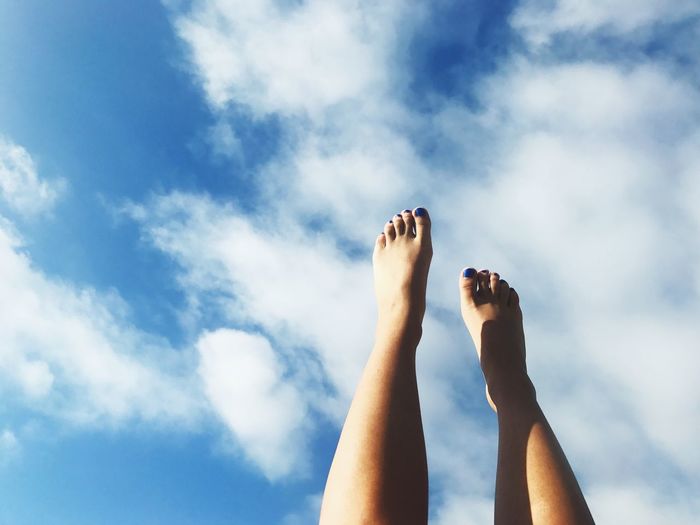 Low section of woman feet up against cloudy sky