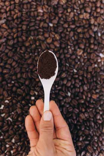 Cropped hand holding spoon against white background