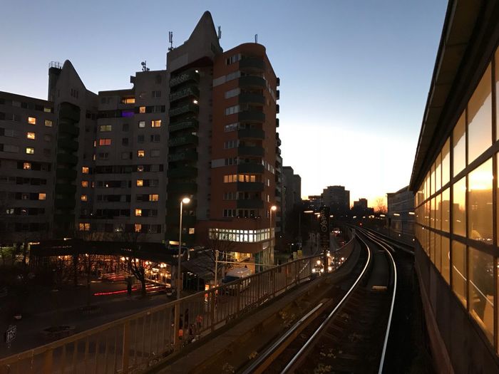 Illuminated railroad tracks in city against sky