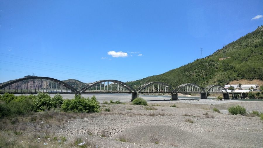 Bridge over mountain against blue sky