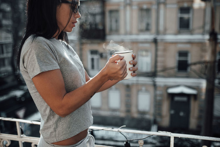 Side view of woman drinking coffee in city
