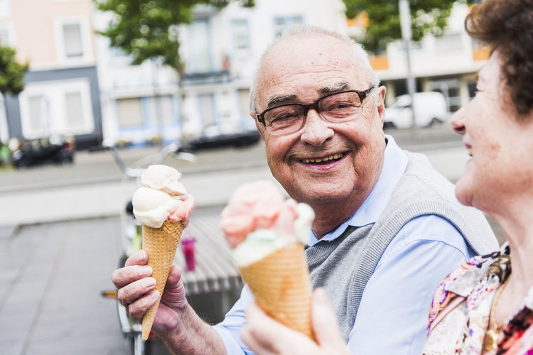 Portrait of happy senior man with ice cream cone looking at his wife